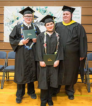 The Murphree family standing in caps and gowns at GBC's Ely Center graduation.